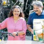 An elderly couple walking in the park with their bicycle