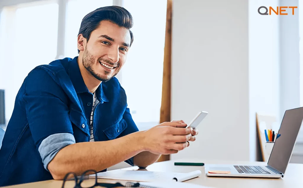 A happy QNET distributor working on his laptop